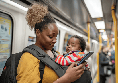 Lady holding a baby looking at her mobile phone